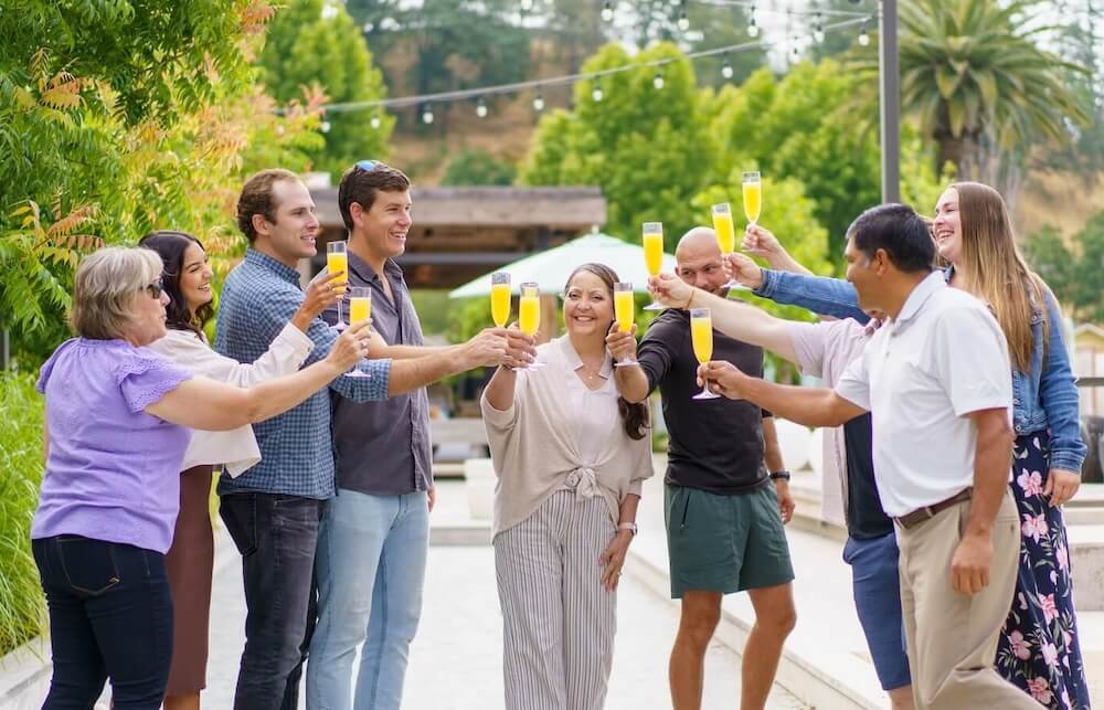 group of friends toasting with mimosas outside at a garden