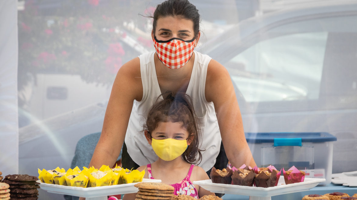 woman with child wearing masks showcasing muffins