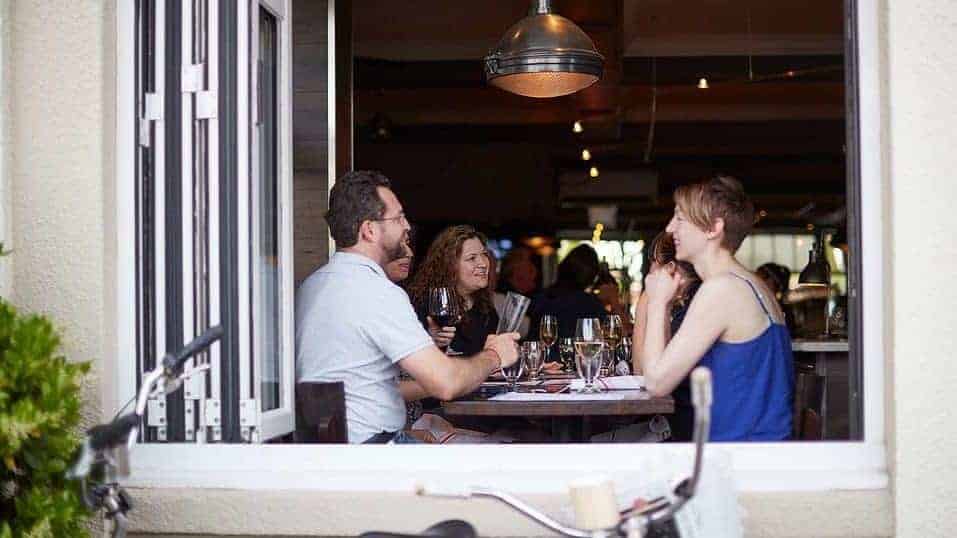 view from outside of window looking into table with people chatting