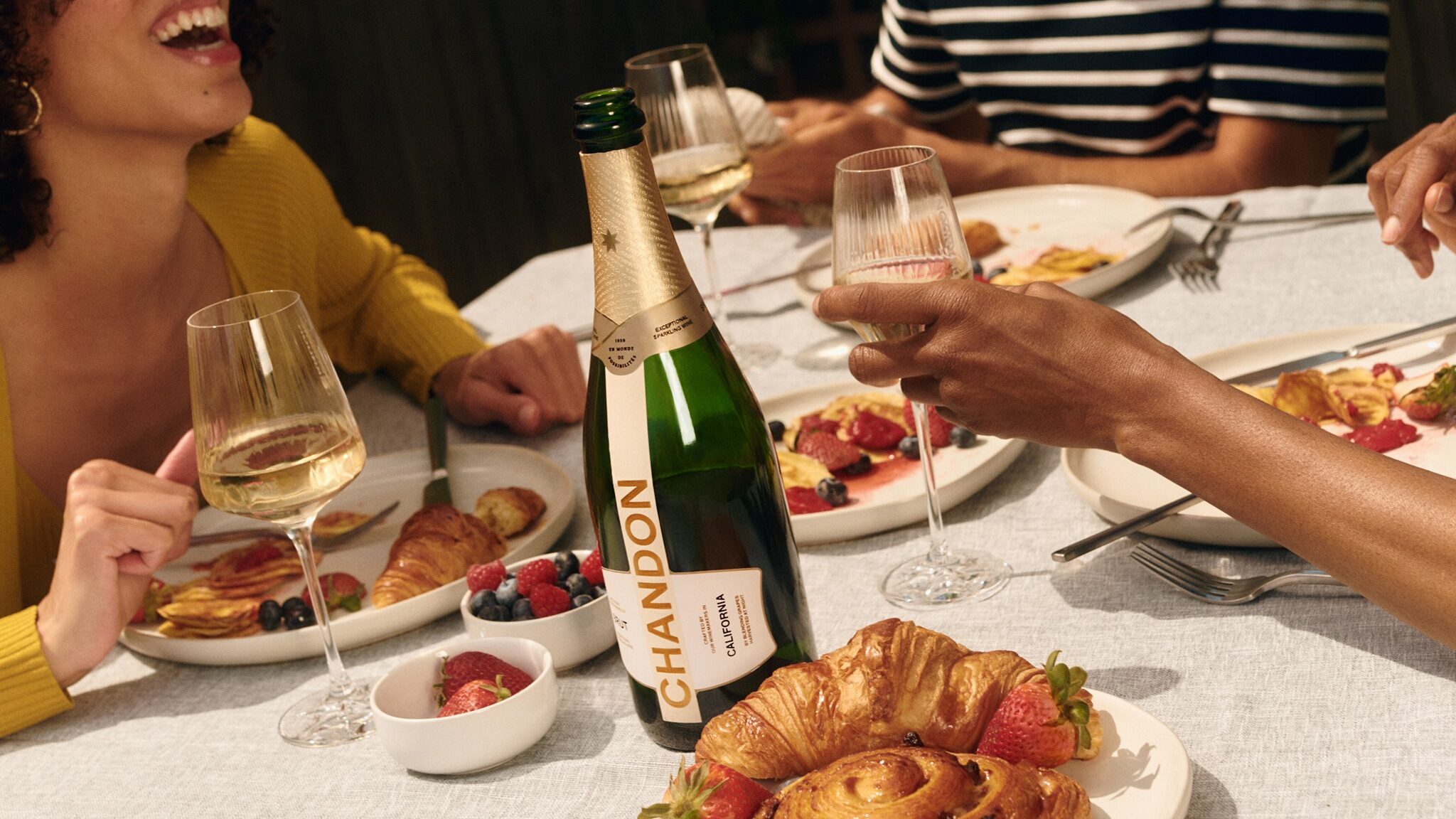 bottle of chandon california on able with people eating and toasting