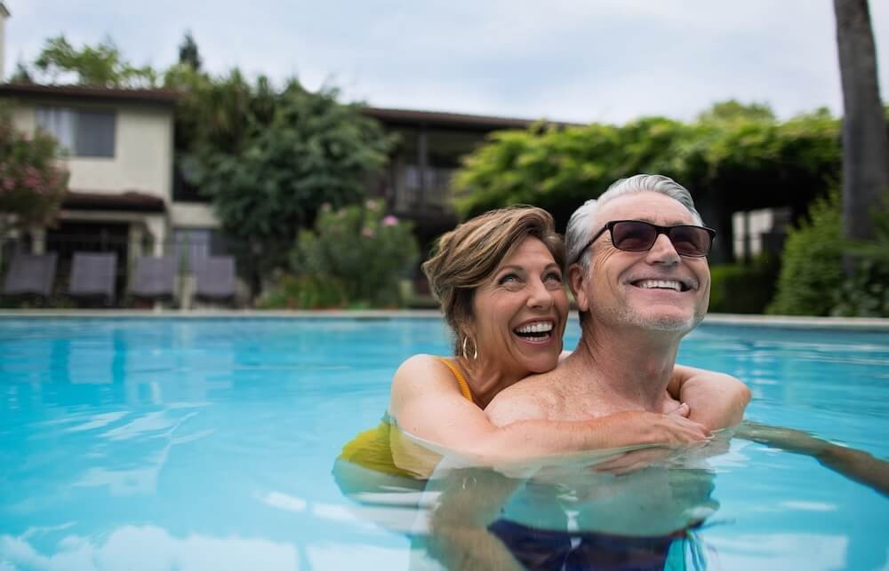 older couple hugging inside pool