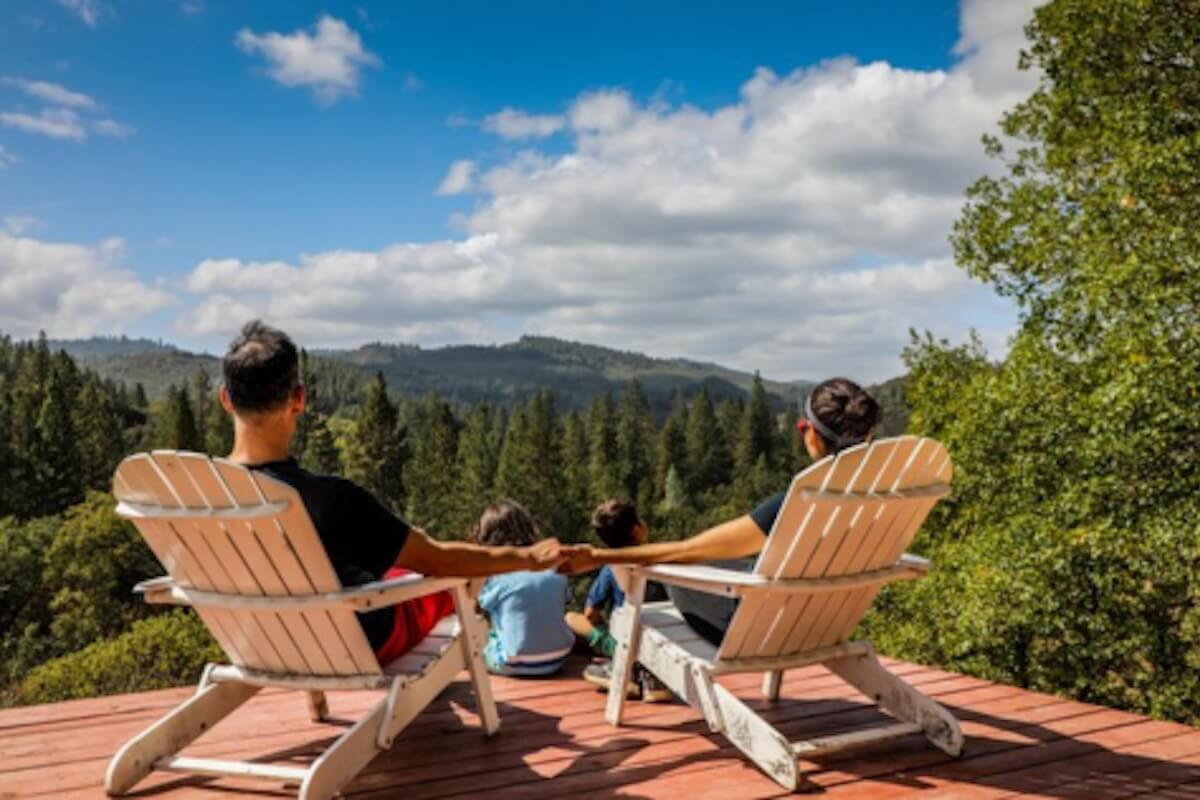 couple sitting on chairs overlooking the valley on a deck with children