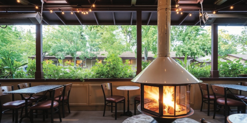 inside of hotel lobby restaurant area with tables chairs and fireplace