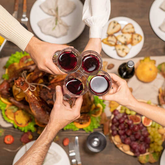 wine glasses held over table of food