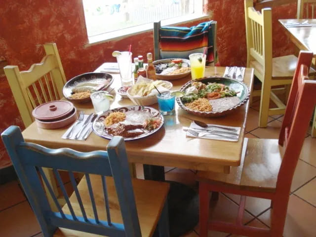 photo of table inside restaurant with mexican food and colorful wooden chairs
