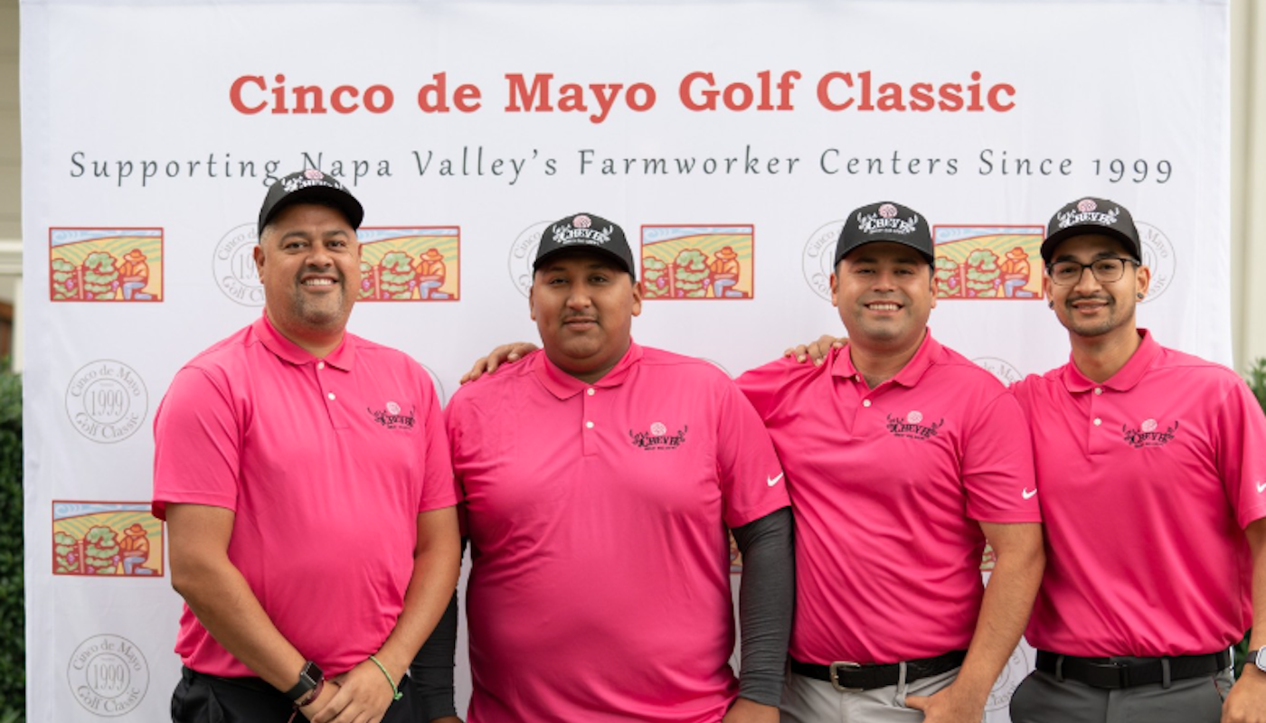 men posing in front of cinco de mayo golf classic sign