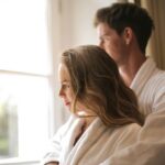 couple hugging in bathrobes in front of window of roman spa hot springs resort bedroom