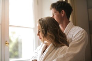 couple hugging in bathrobes in front of window of roman spa hot springs resort bedroom